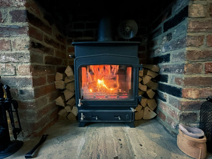 a wood burning stove with a stack of firewood nearby