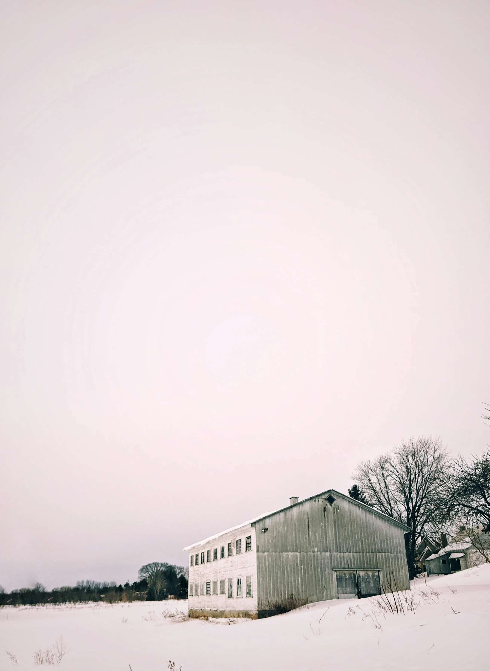 a barn on an empty field with the sky above