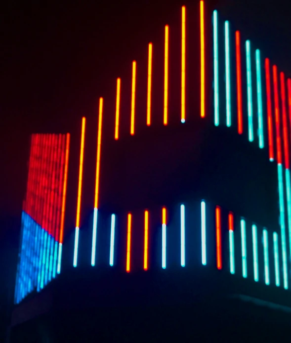 an illuminated object with vertical lines of colors in front