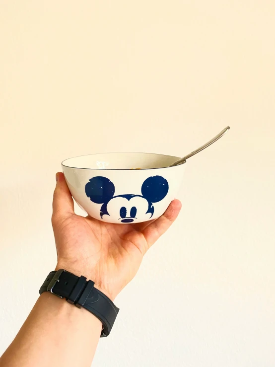 a hand is holding a bowl with a blue panda face painted on it