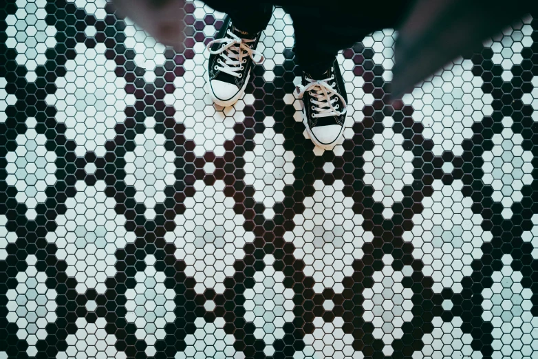 a pair of black and white sneakers are on top of an abstract patterned tile