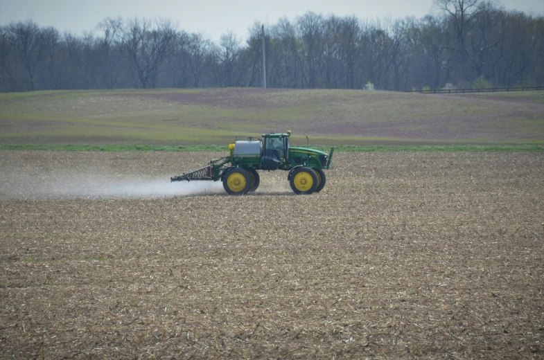 a tractor is sprinkling crops in an open field