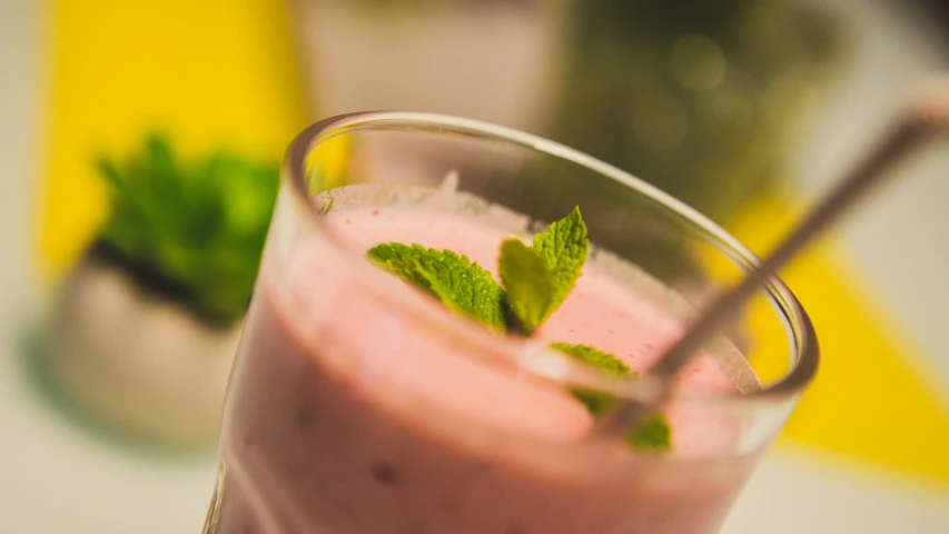 a smoothie in a glass with mint sprig on top