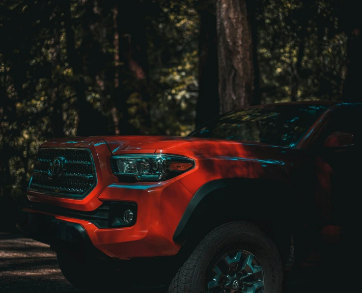red pickup truck parked in the woods with trees