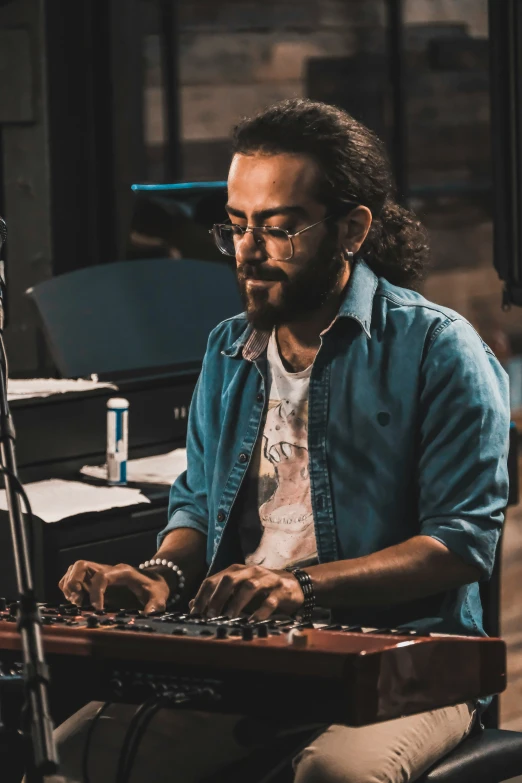 a man sitting at a piano keyboard with a large instrument behind him