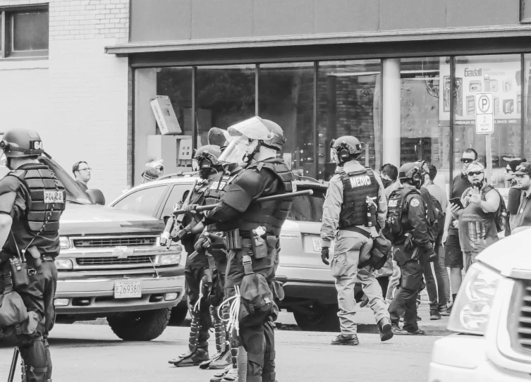 police officers wearing full protective gear stand near a building