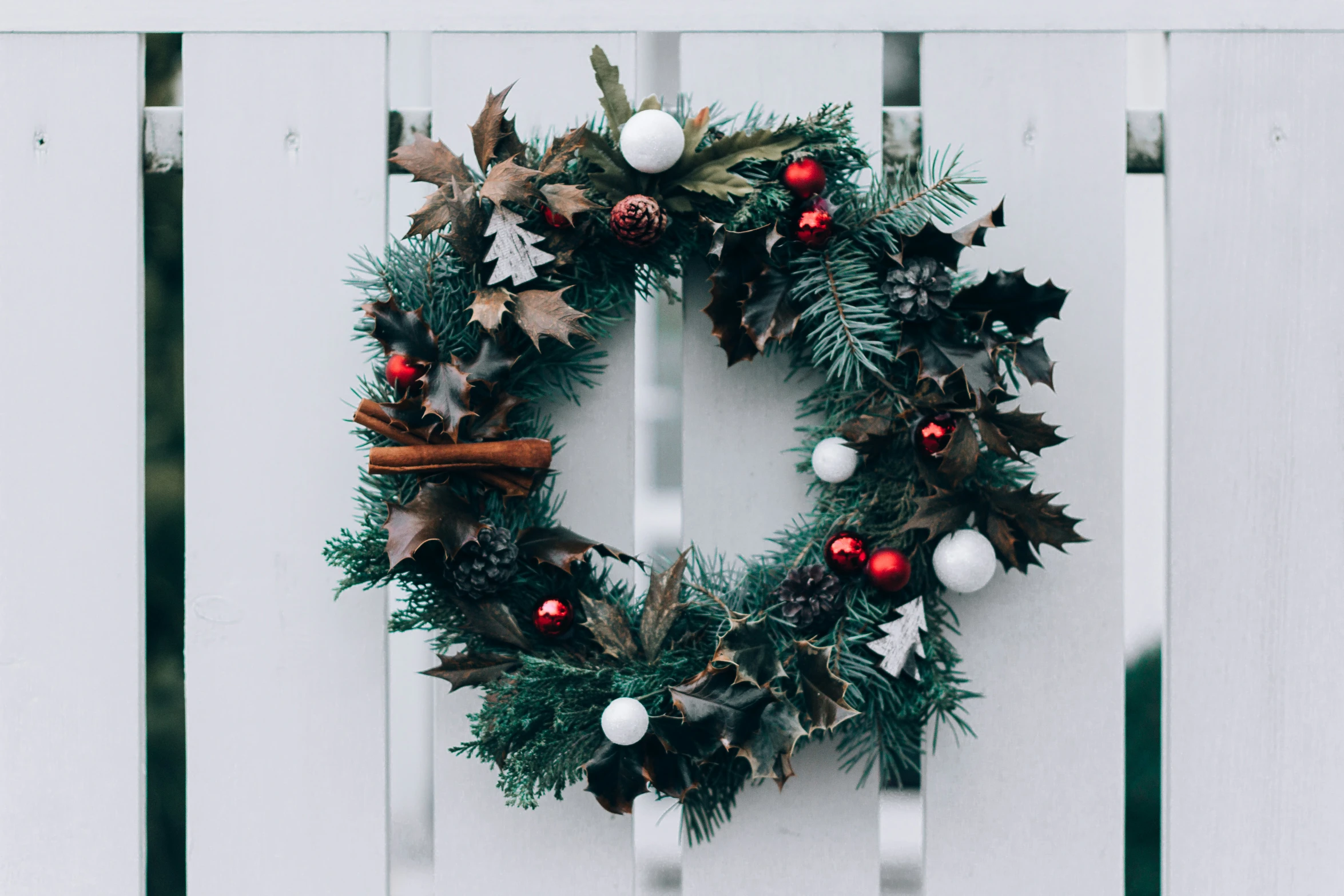 wreath on white fence with red, white and green ornaments