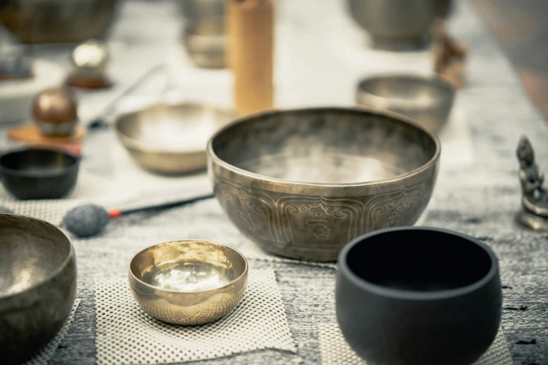 a table topped with lots of metallic bowls and other antique items