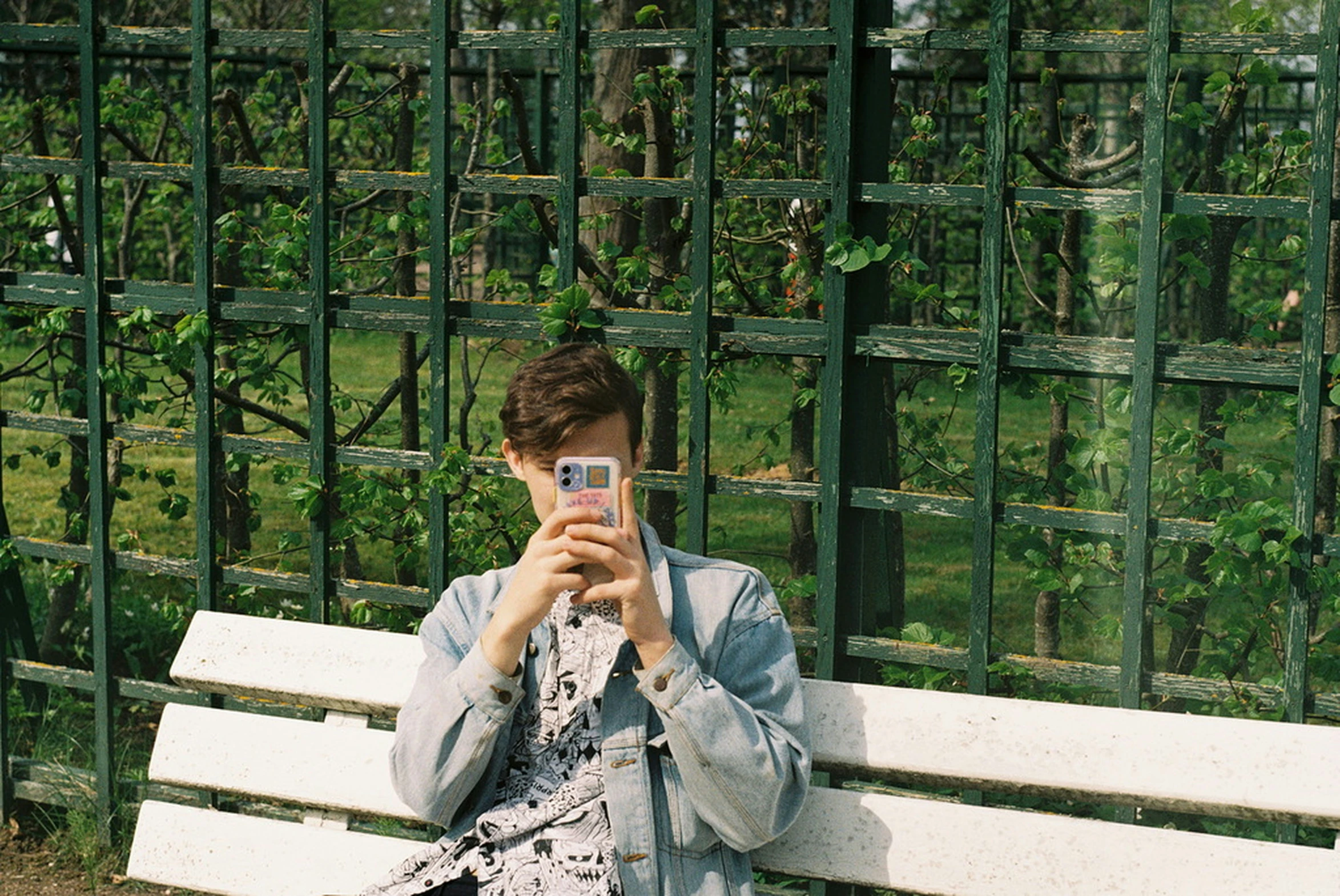 a young woman sitting on a park bench looking at her phone