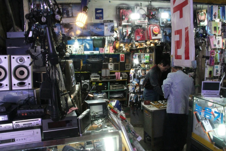 two men working in a shop filled with electronics