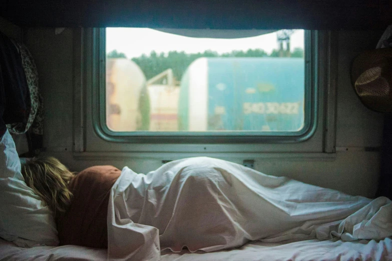 a woman is sleeping in a bed near the window