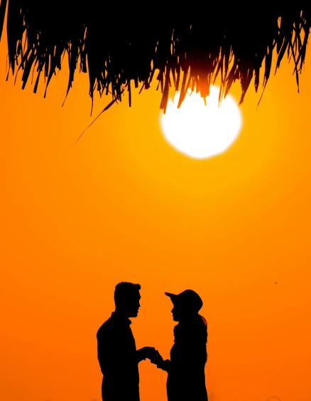 a silhouetted picture of two people shaking hands in front of an orange and yellow sky