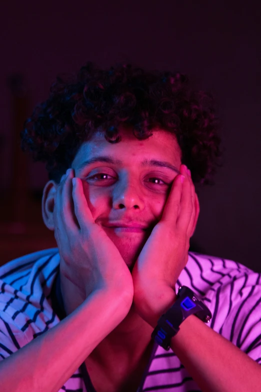 a  with curly hair sitting at a table in a purple lit room