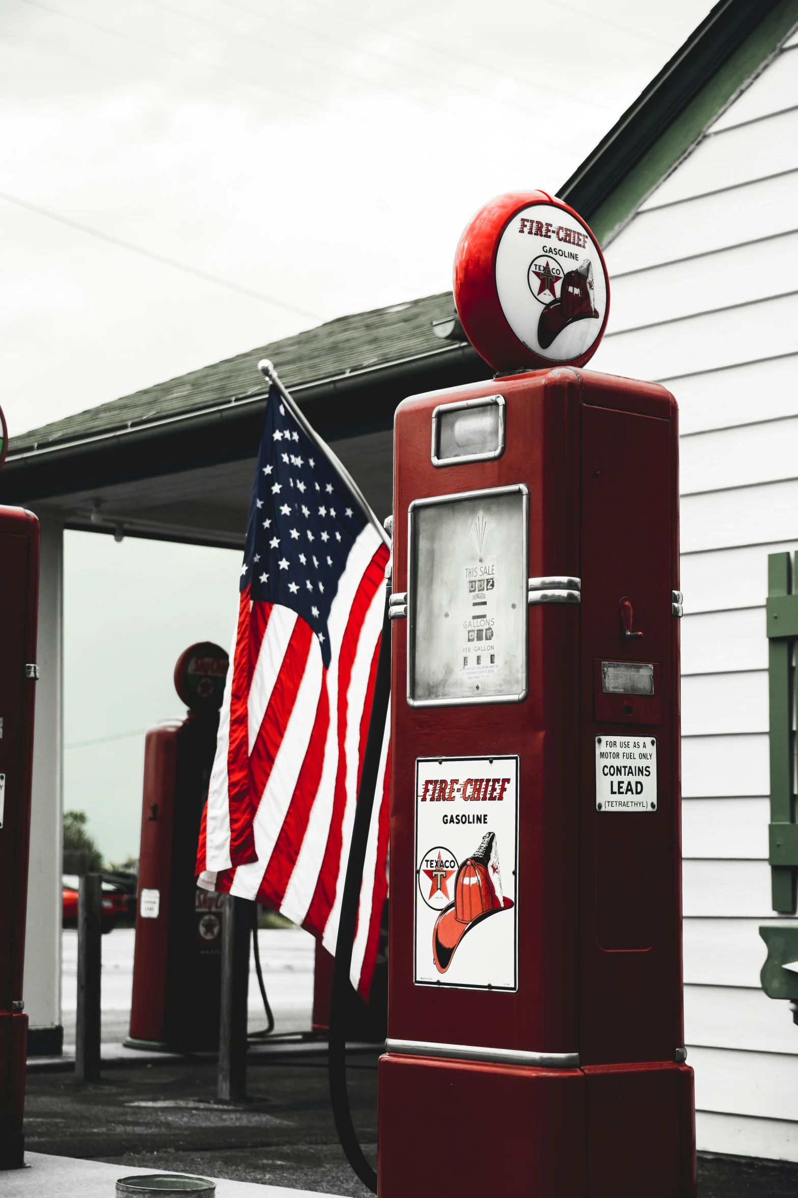 an american flag hanging on the top of a red gas pump