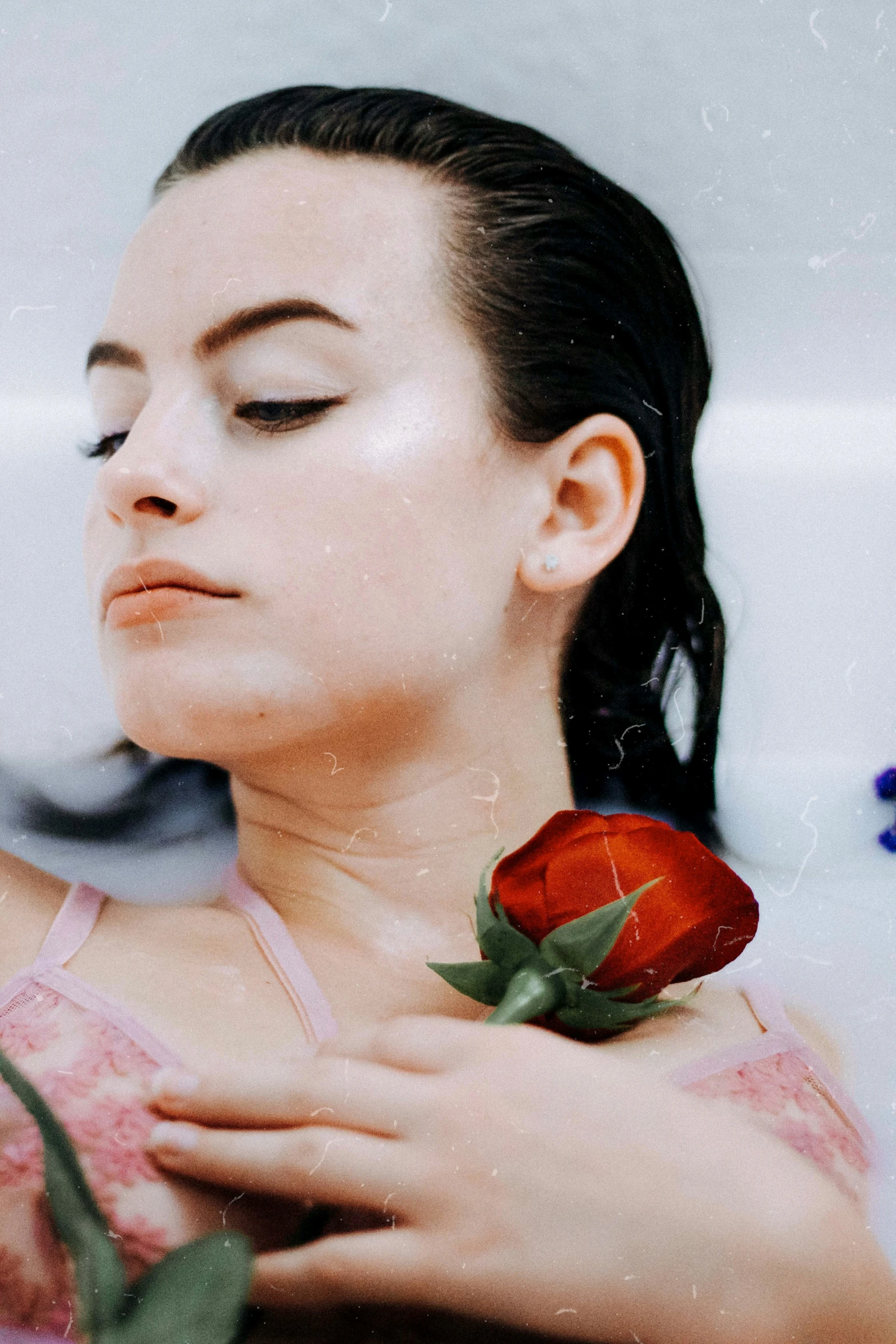 a woman holding a rose up to her face