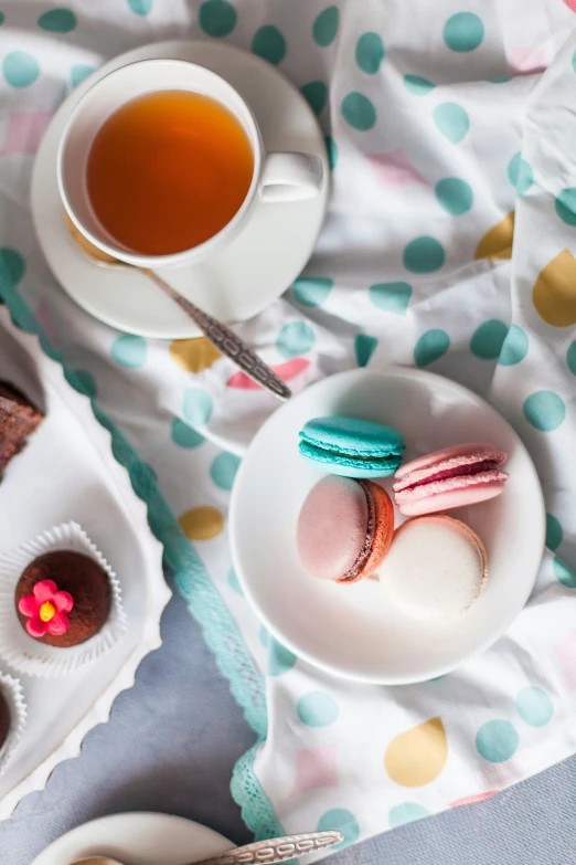 an arrangement of pastries and tea are displayed on a bed