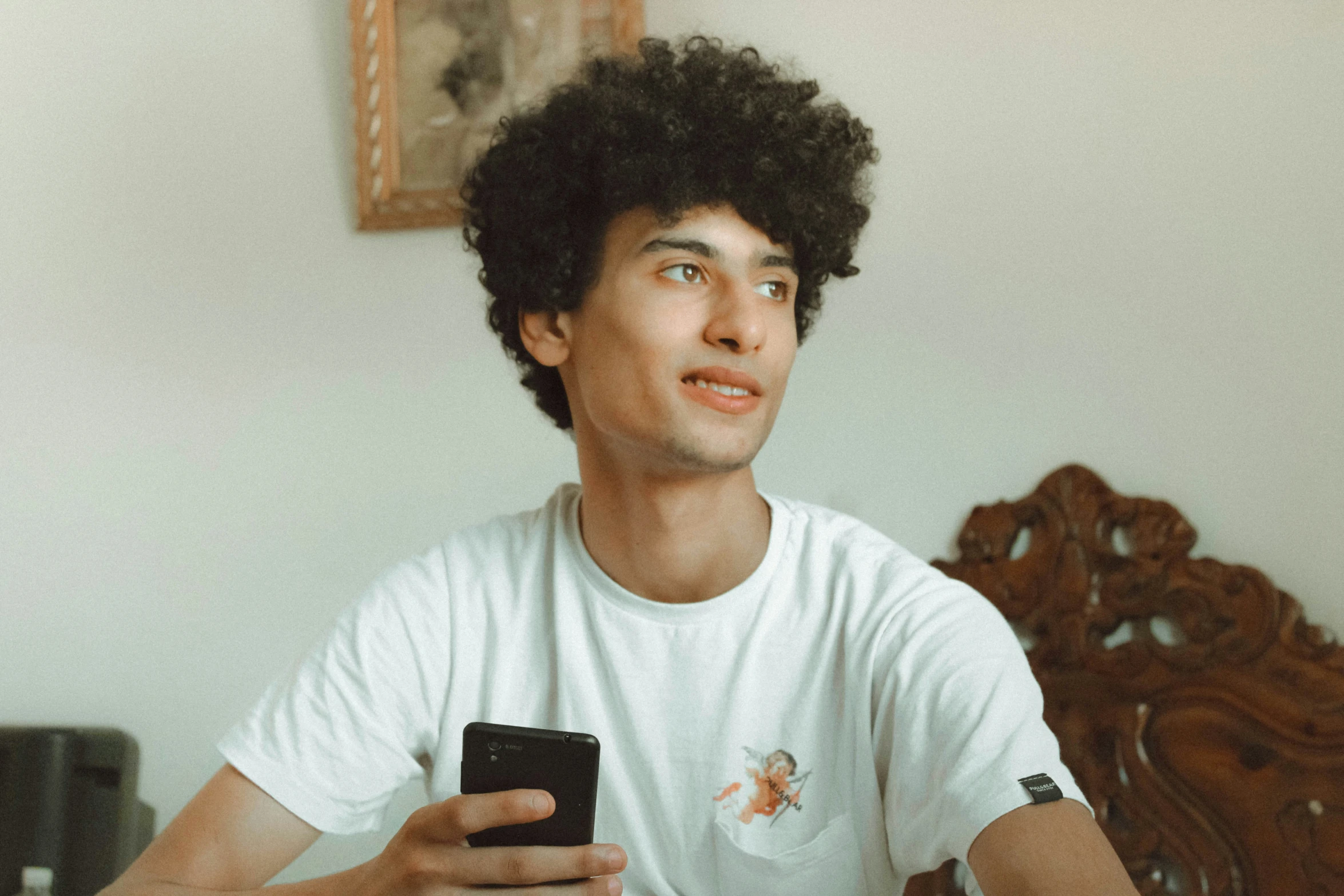 a man sitting down on a bed with a cell phone