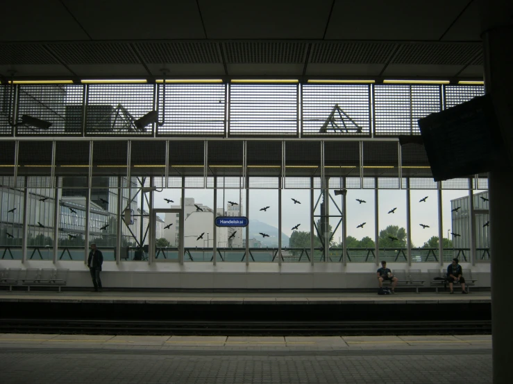 some people sitting on benches next to a train station