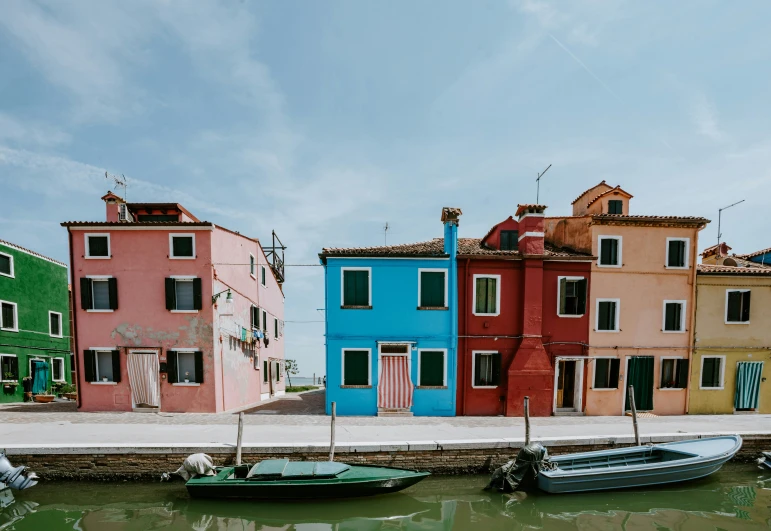 three rowboats and two row houses are parked along a dock