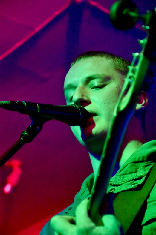 a person with an acoustic guitar stands in front of a microphone