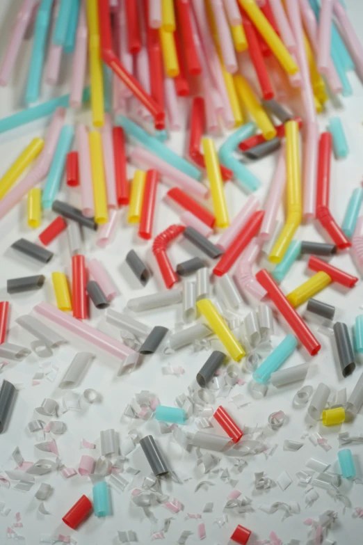 assorted colored toothbrushes with one half peeled toothbrush and several scattered ones