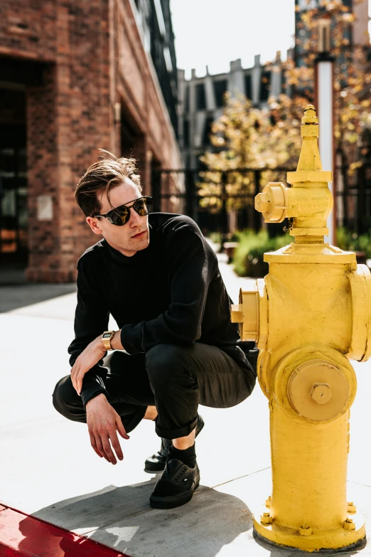 a man is posing near a fire hydrant on the sidewalk