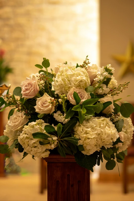 white flowers arranged in a wooden vase on a church pew