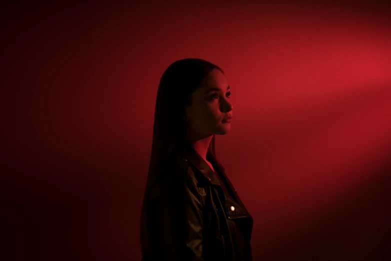 the woman standing in front of a red background is looking upward