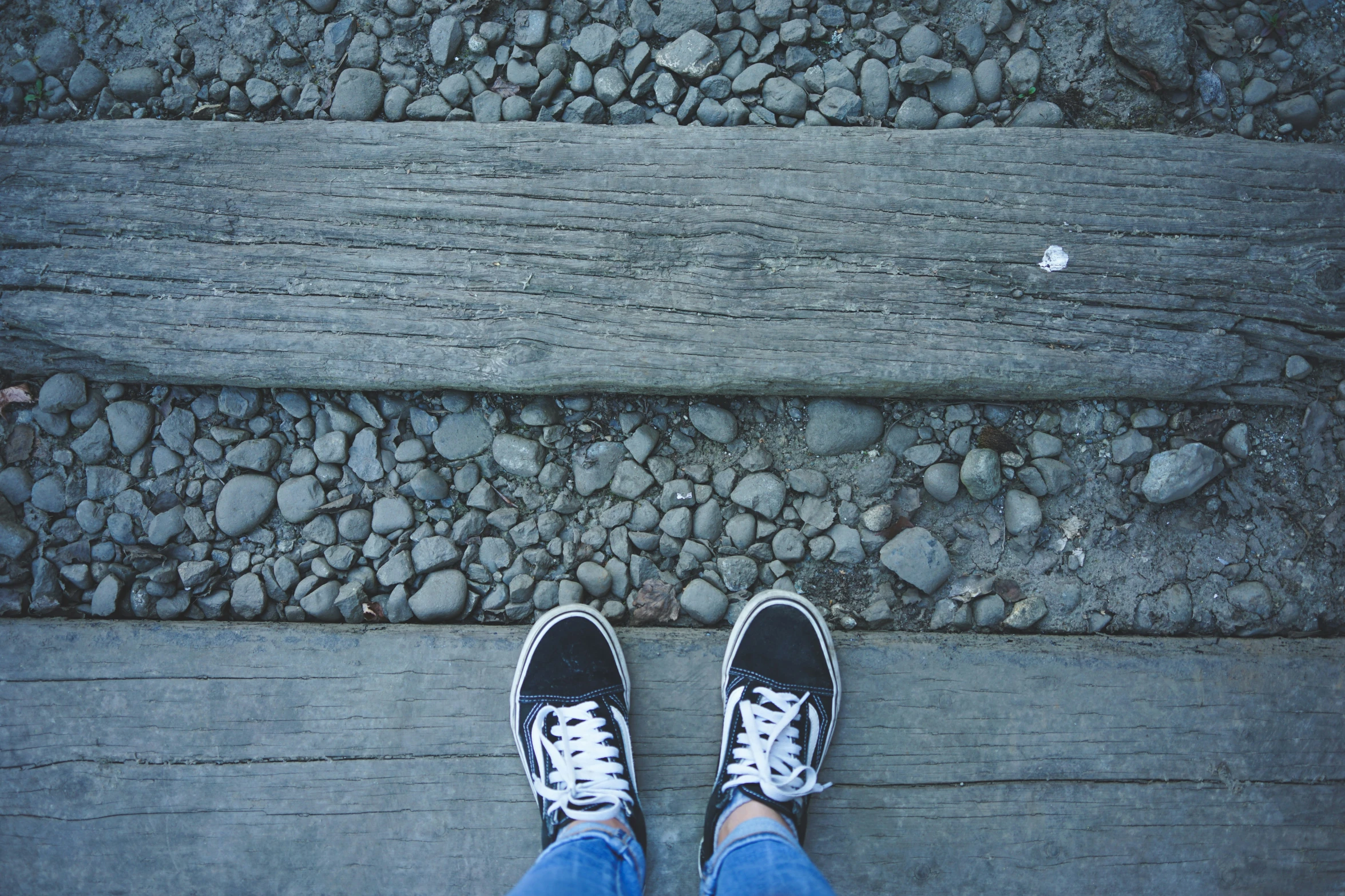 the person in sneakers stands on a wood walk