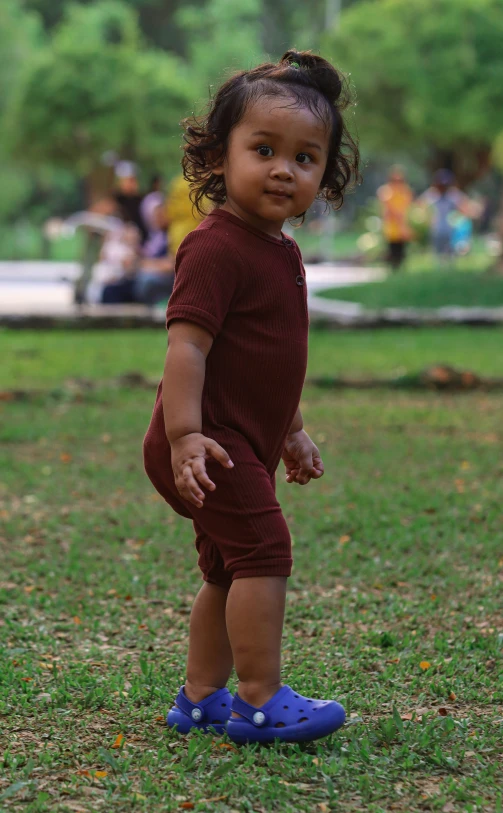 a small child wearing blue shoes and standing on grass