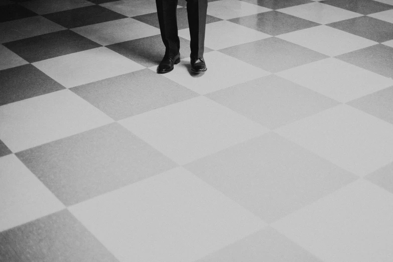 a man in a suit and tie standing on a checkered floor