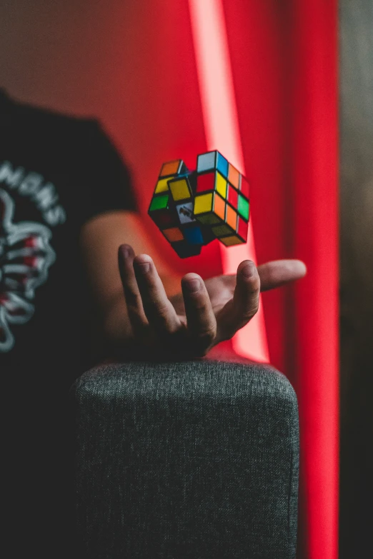 a colorful cube being held by a person in a black shirt