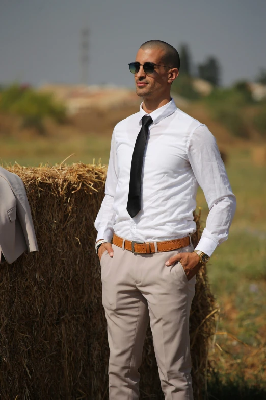 a young man standing next to a hay bail