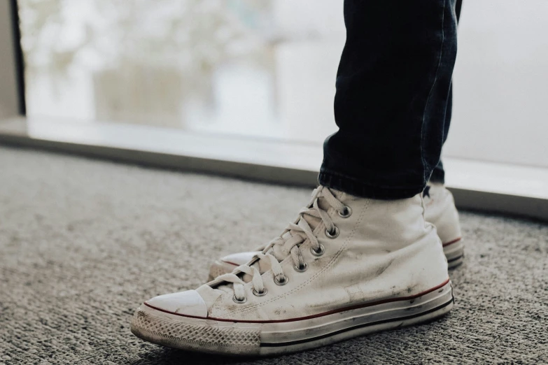 a person wearing sneakers standing next to an airport door