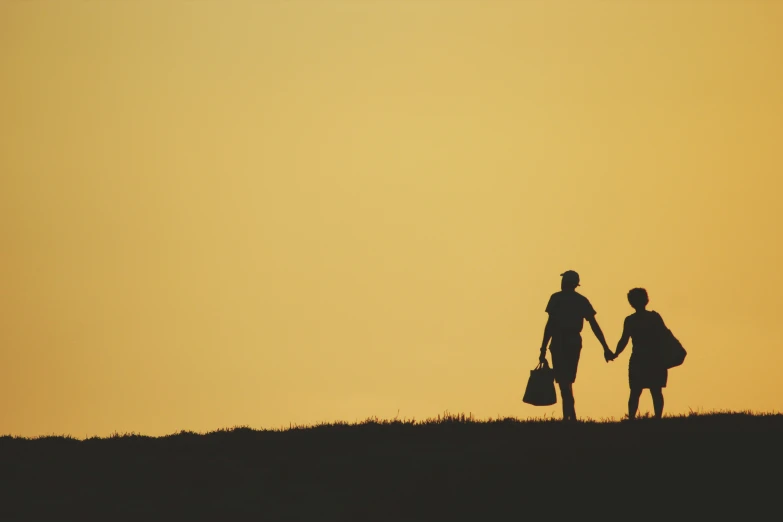 a silhouette of two people holding hands, walking up a hill