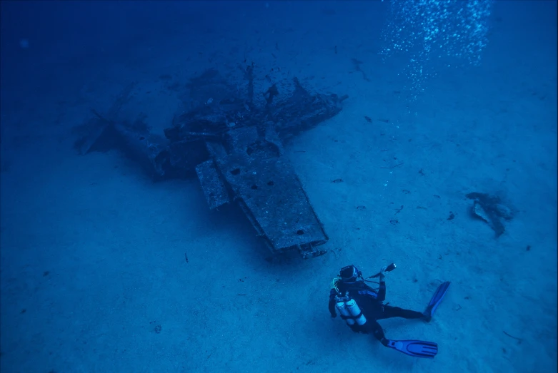 a scuba person wearing a diving mask dives under the ocean floor