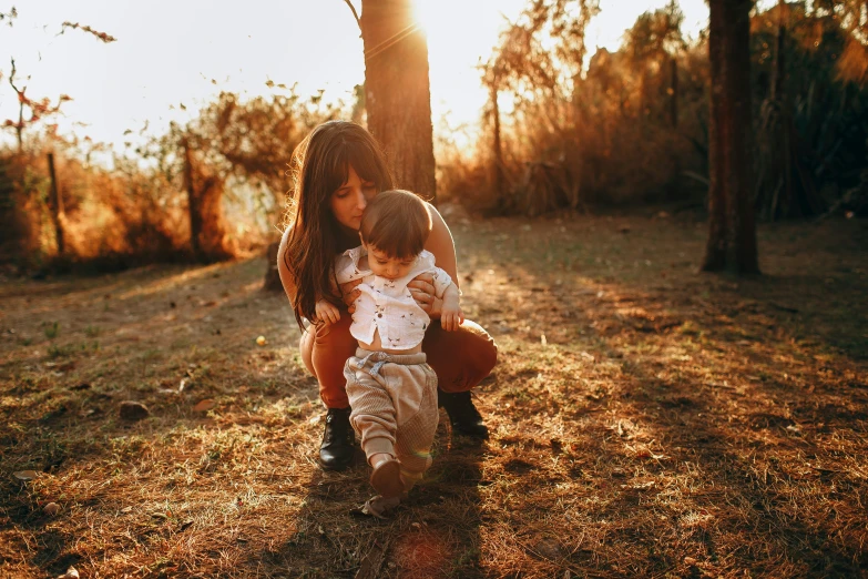 two children hug their arms in front of a tree