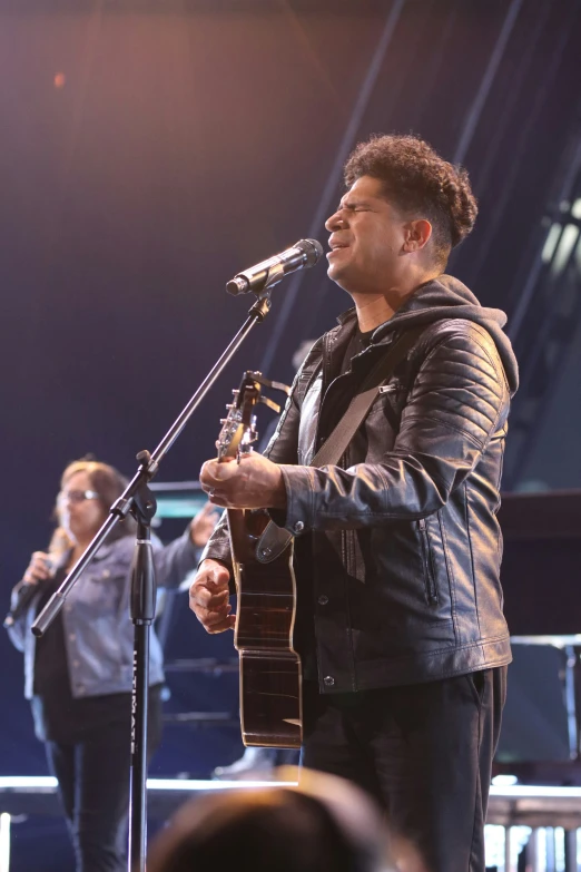 a person holding a guitar and singing into a microphone