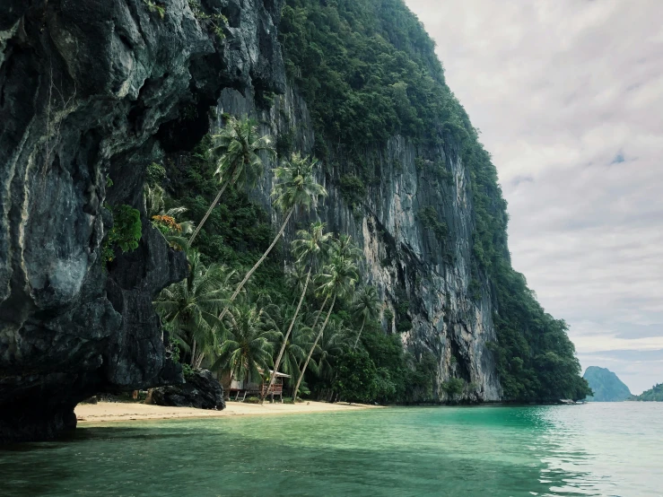 a sandy shore surrounded by water with hills in the background