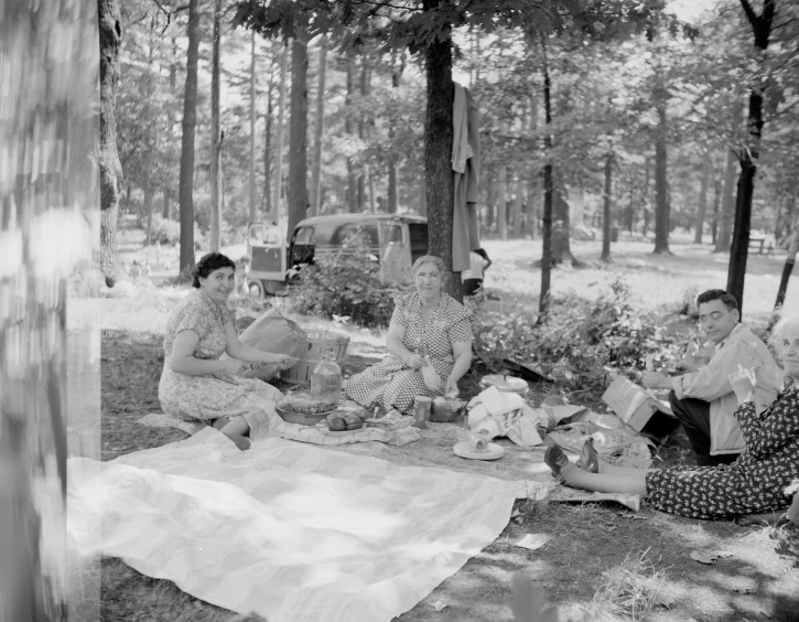 group of women eating on a blanket in the woods