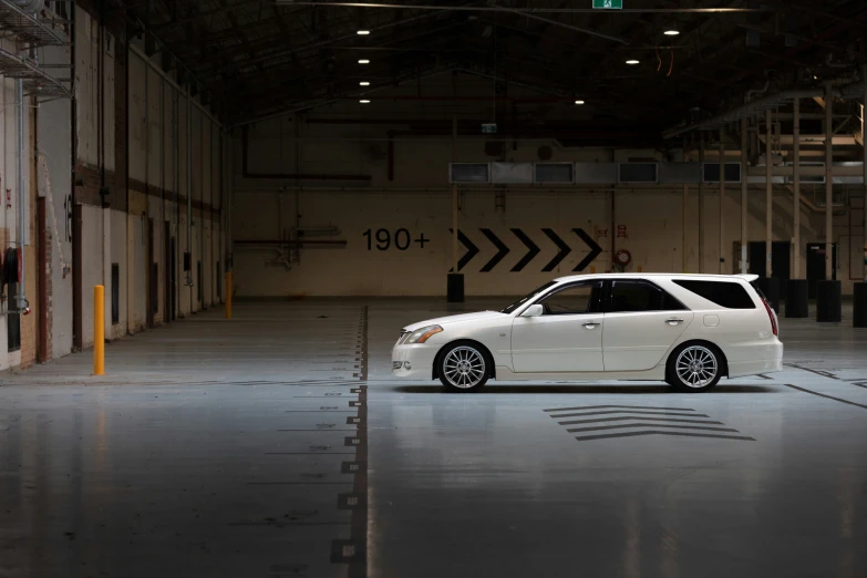 the small white car is parked in an empty garage