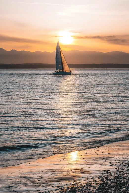 a sailboat sailing down the ocean during sunset