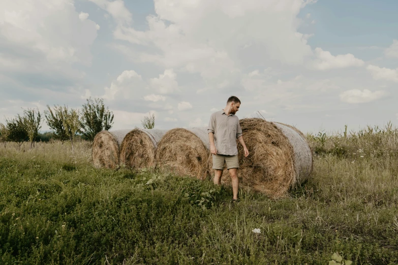 the young man is standing by hay balls