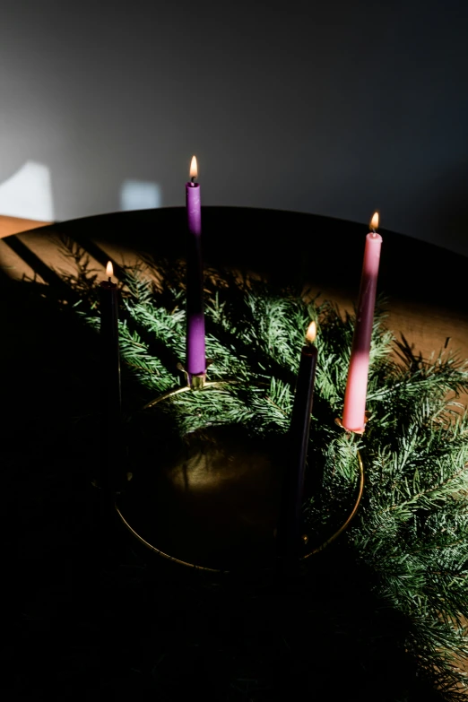the three candles are purple in color and arranged in a circle on the table