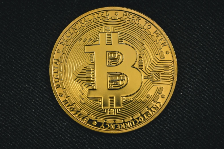 a golden bit coin on a black surface