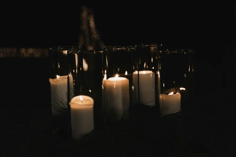 several candles lit in the dark and surrounded by other candles