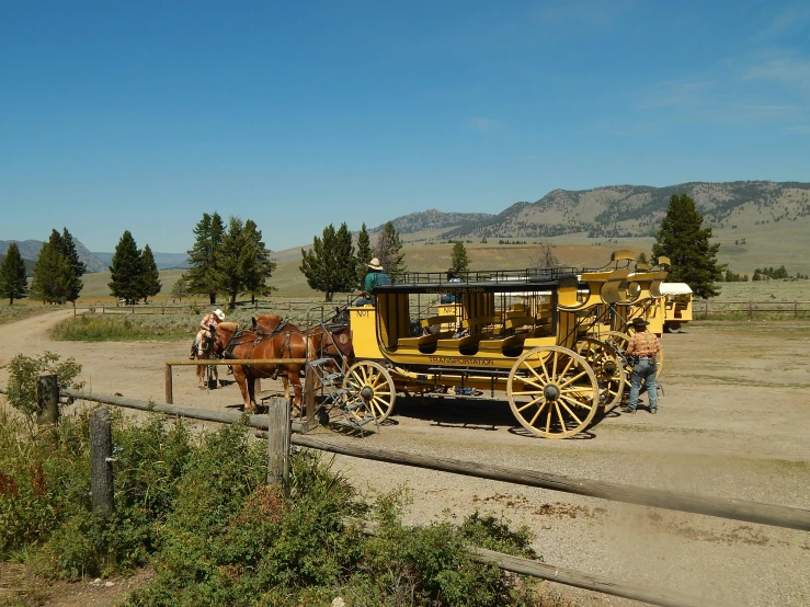 the people are driving the yellow carriage in the field