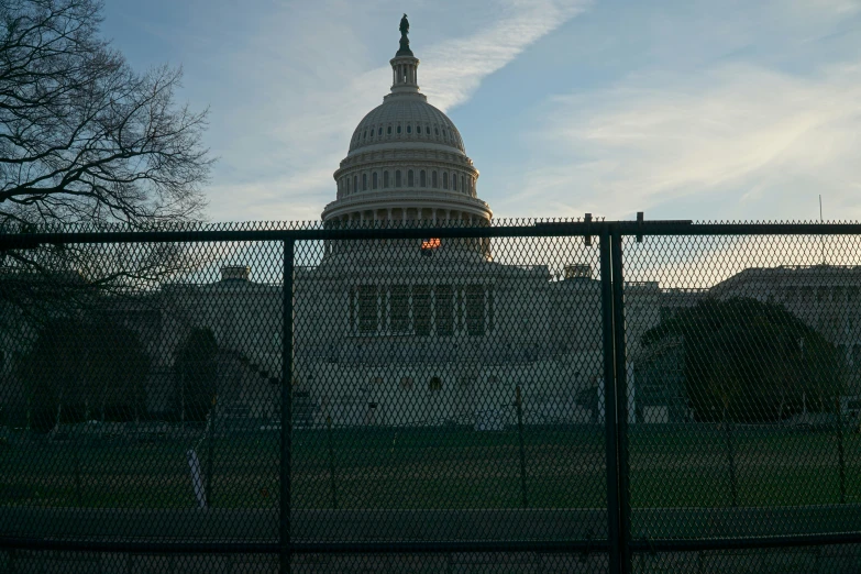 the capital building is seen through a fence