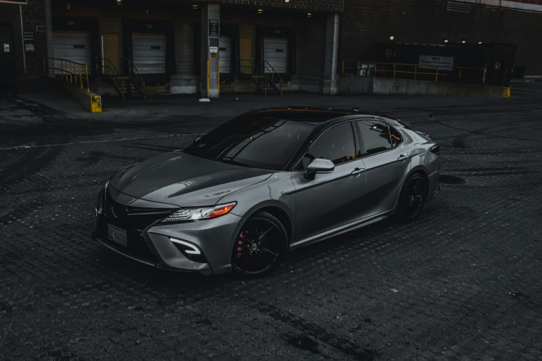 the grey sports car is parked in front of an industrial building