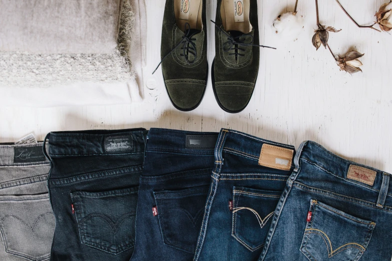 jeans, broccoli, and shoes sit on the floor next to a blanket